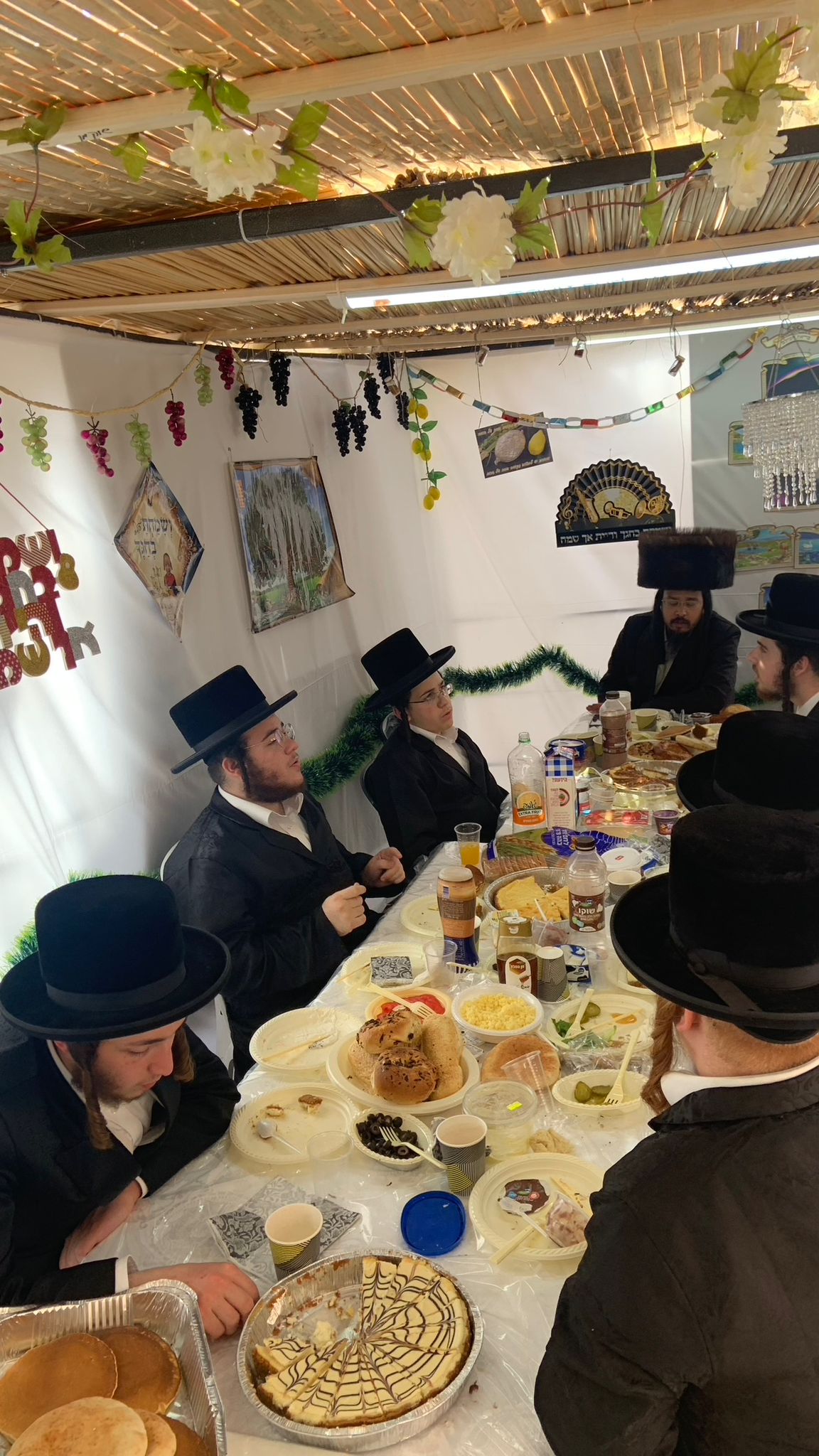 Guests around a table in the sukkah during Chol Hamoed