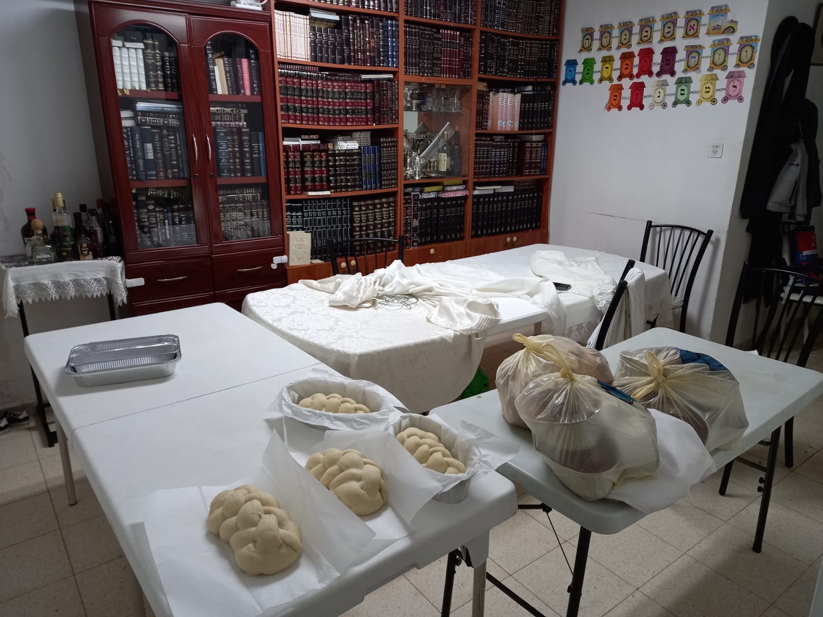 Tables, challos and food being prepared before Shabbos